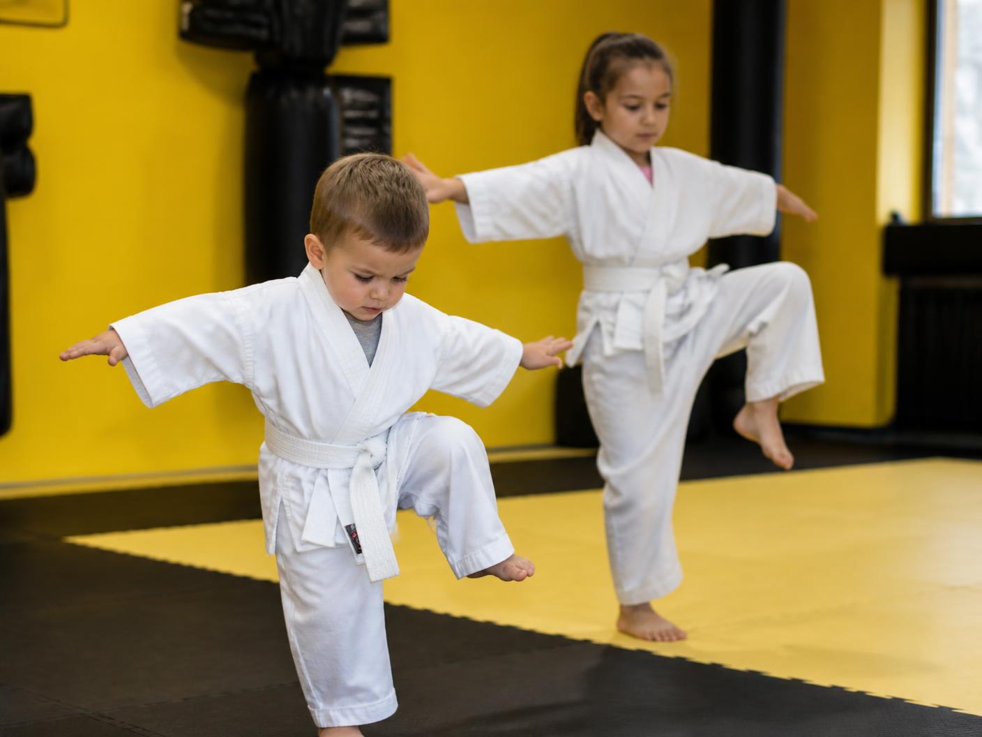 A three-year-old and a six-year-old attempting the same balance drill at Pride Martial Arts