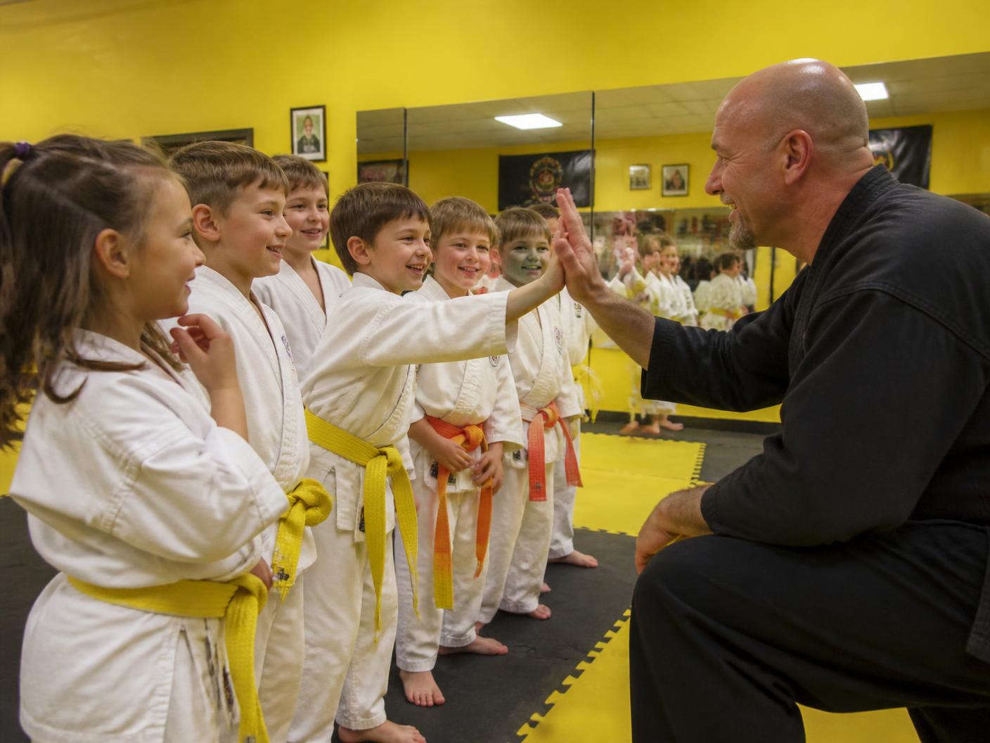 Young students high-fiving their instructor at Pride Martial Arts