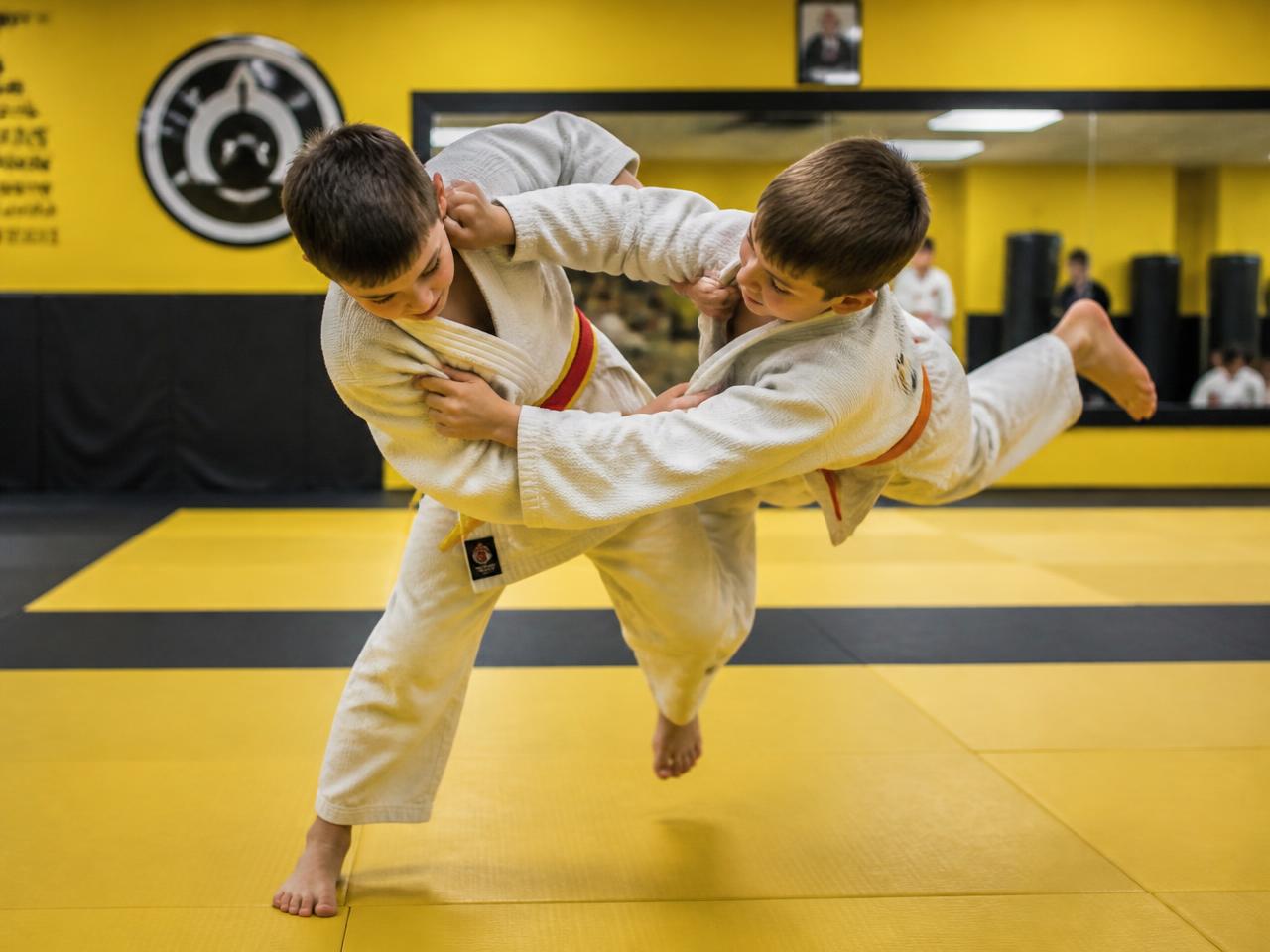 A young judo student throwing a partner with a hip throw